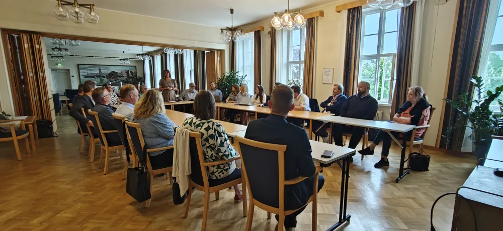 Ett tjugotal personer på möte i ett stort rum i stadshuset