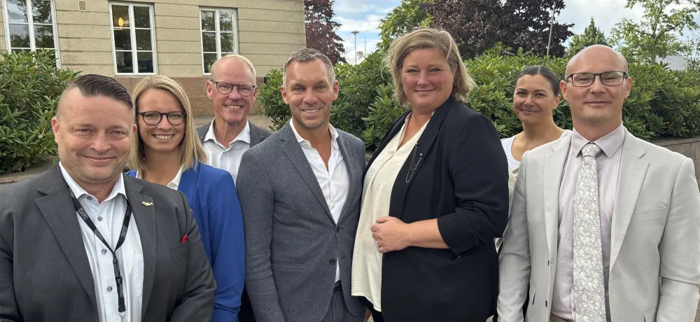En samling personer står uppradade framför Mariehamns stadshus.